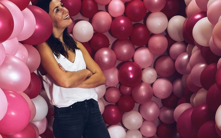 Frau lehnt an pinken Ballons 