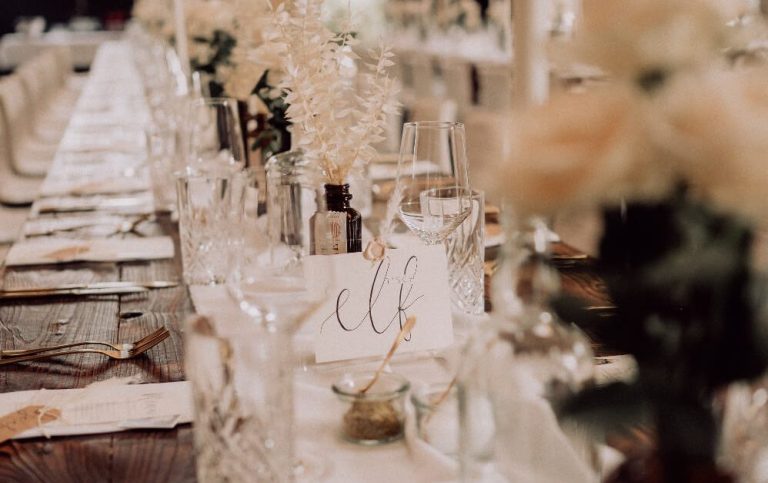 Lange gedeckter Tisch bei Hochzeit mit weißem Leinen-Tischläufer