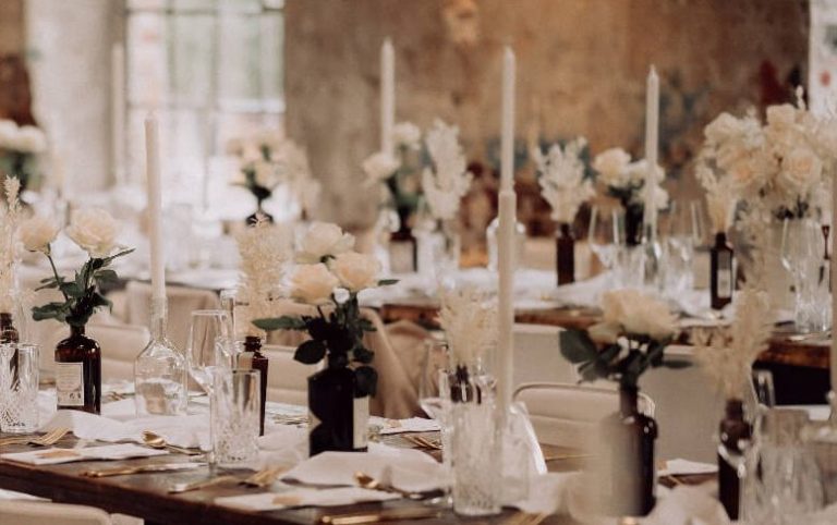 Festliche Hochzeitstafel mit Gin Vasen, Rosen und weißen Kerzen